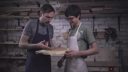 Two carpenter masters discuss a piece of wood (round timber) in the workshop