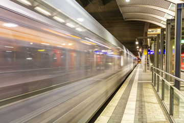 Vorbeifahrender weißer Zug an einem Bahnhof in Deutschland mit leerem Bahnsteig