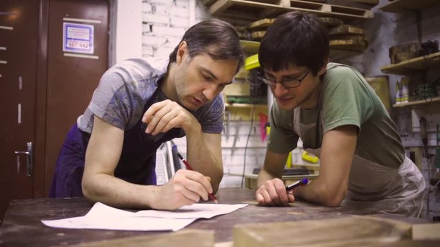Slow Motion: Two carpenters discuss drawing (round wood) in the workshop
