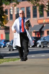 Handsome Senior Male Doctor Smiling With Notebooks Walking