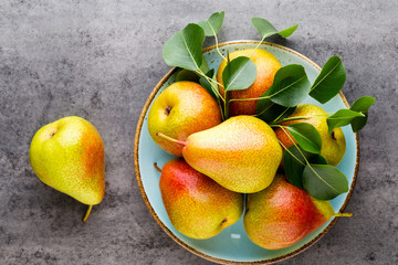 Fresh bio pear with leaves on the plate. Gray stone table.
