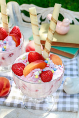 Ice cream dessert with fresh strawberries, peaches and crispy wafer rolls.