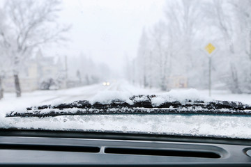 Road covered with snow seen through windshield.