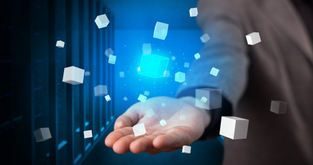 Person holding hologram projection displaying white cubes in server room
