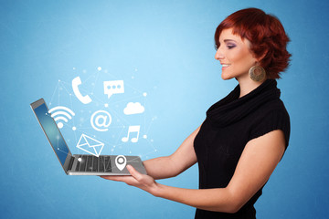 Woman holding laptop with online services symbols
