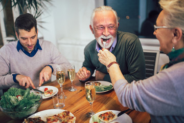 Multi generation family enjoying meal around table at home