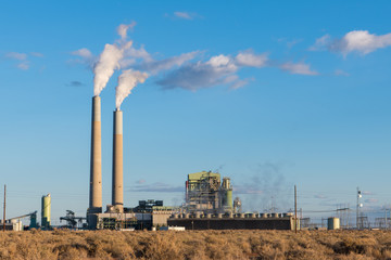 Fototapeta na wymiar A coal-fired electrical power plant with smokestacks emitting plumes of smoke in the southwestern United States