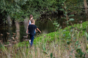 children walk in nature, along the pond