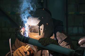 A professional welder welds a pipe with a diameter of DN50 for a process pipeline to an oil refinery in Russia.