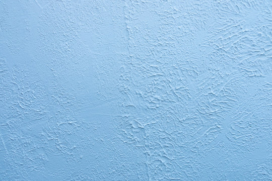 Blue textured wall. Decorative plastering close-up photo. Surface with stucco daub