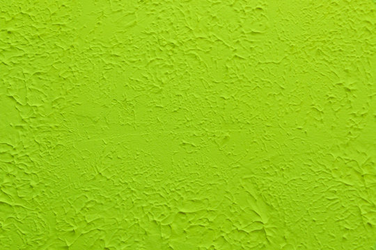 Green textured wall. Decorative plastering close-up photo. Surface with stucco daub