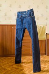 Jeans after washing independently stand on floor.
