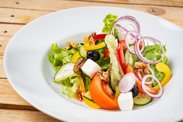 Greek salad with feta cheese on the wooden background