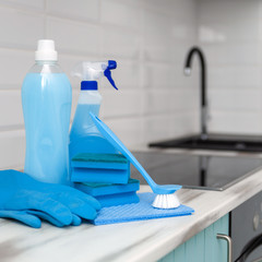 A set of blue cleaning products and tools for cleaning is on the kitchen table.