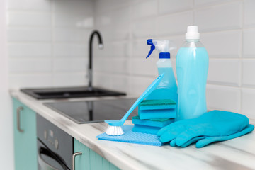 A set of blue cleaning products and tools for cleaning is on the kitchen table.