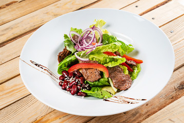 salad with beef, red beans and vegetables, wooden background