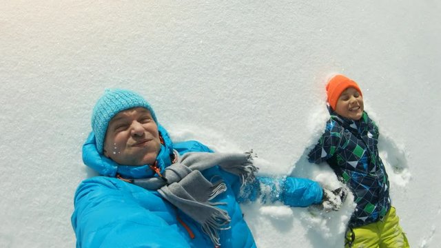 Father and son falling into the snow in slow motion