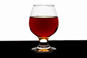 A glass of whiskey with ice or brandy and a square carafe on a black dish isolated against a white background. Whiskey with ice in the glass on a white background.