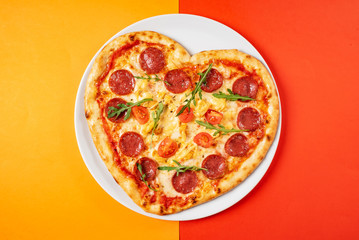Heart shaped pizza with meat and vegetables. Food concept of romantic love for Valentines Day.