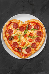 Heart shaped pizza with meat and vegetables. Food concept of romantic love for Valentines Day.