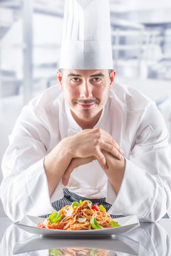 Chef in restaurant kitchen with plate from italian meal spaghetti bolognese