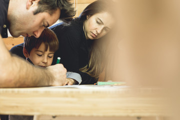 Child painting a picture at home with his parents. Couple assisting your son in drawing a picture.