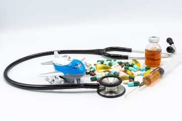 Toy airplane with black stethoscope and assorted drugs imply medical tourism on white black ground
