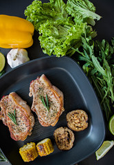 Grilled chicken in a grill pan, decorated with spices for meat, rosemary, vegetables on a dark background. View from above.