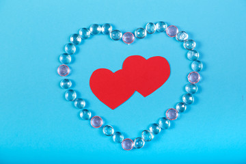 The heart of white beads and a red heart in the middle on a blue background.