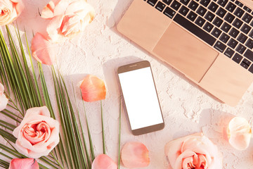 Flat lay of stylish composition with laptop, mobile phone. tropical palm leaf, pink rose flowers,...