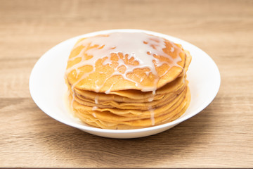 Pancakes with condensed milk on a white light background. A stack of pancakes with sweet sauce. Close up view.