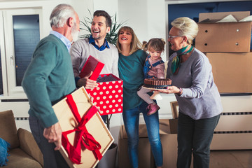 Grandmother and grandfather bring a gift for moving into a new apartment to their children