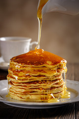 Pancakes with honey, nuts and raisins with a cup of coffee