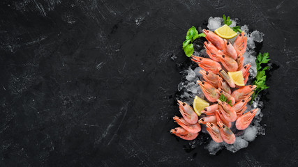 Shrimp with ice and lemon. On the old background. Top view. Free copy space.