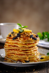 Pancakes with honey, nuts and raisins with a cup of coffee