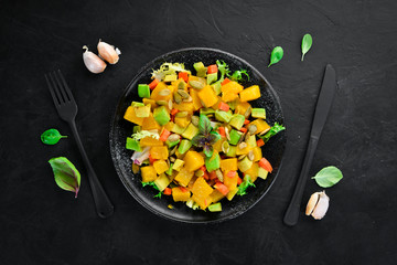 Salad of pumpkin, avocado and pumpkin seeds. On a black background. Top view. Free space for your text.