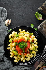 Pasta with vegetables. On a black background. Top view. Free space for your text.