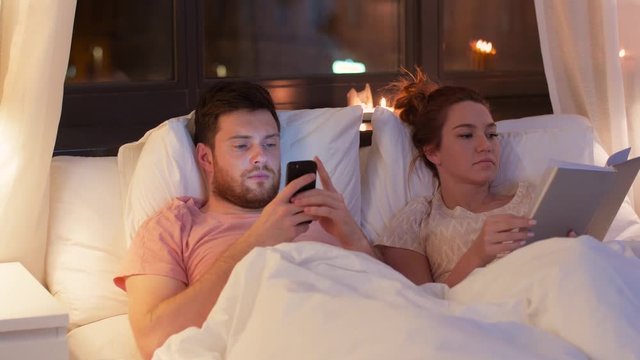 technology, internet and communication concept - couple using smartphones in bed at night