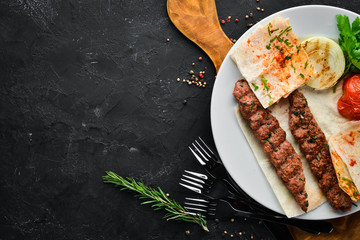 Lamb Kebab. Pita bread and spices. On a black background. Top view.