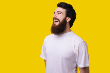 Fototapeta premium Close up portrait of cheerful middle aged man with beard standing and smiling over yellow background