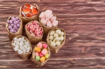 Fototapeta na wymiar candies, lollipops, caramel, in paper bags on wooden background