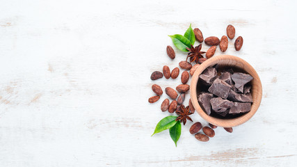 Dark chocolate in a bowl on the old background. Top view. Free copy space.