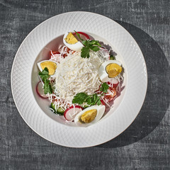 Salad with eggs, cheese and spring vegetables, radishes with tomatoes. closeup on the table.