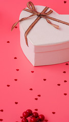 St. Valentine day background. Gift box with gold ribbon and lights on a pink background. Holiday background