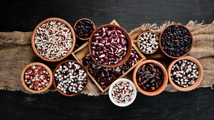 Colored raw beans. On a black wooden table. Top view. Free copy space.