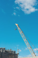 Fototapeta na wymiar Single high crane in construction area with blue sky