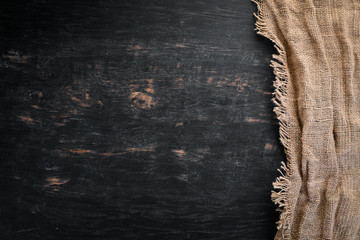 Old linen fabric on a black wooden background.