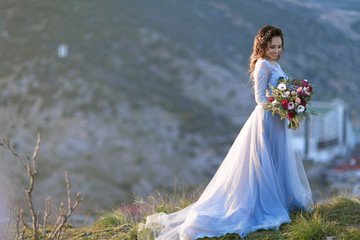 Fototapeta na wymiar Beautiful bride in fashion wedding dress on natural background.The stunning young bride is incredibly happy. Wedding day. .A beautiful bride portrait at sea view