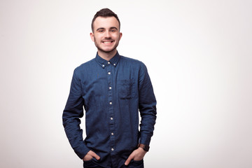 Obraz premium Handsome young man looking at camera. Portrait of young man with hands in pockets. Happy guy smiling