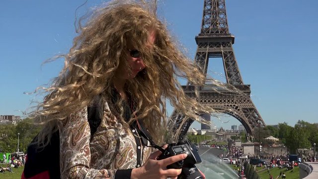 Beautiful woman with hair in the wind captures moments and memories near the Eiffel Tower